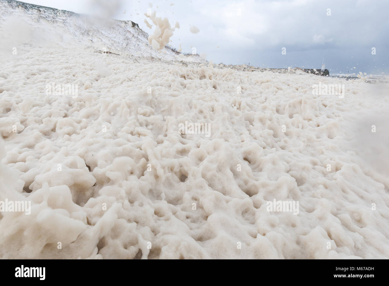 Sea foam on the coast of Northumberland, caused by sea water agitation combined with organic matter. Stock Photo