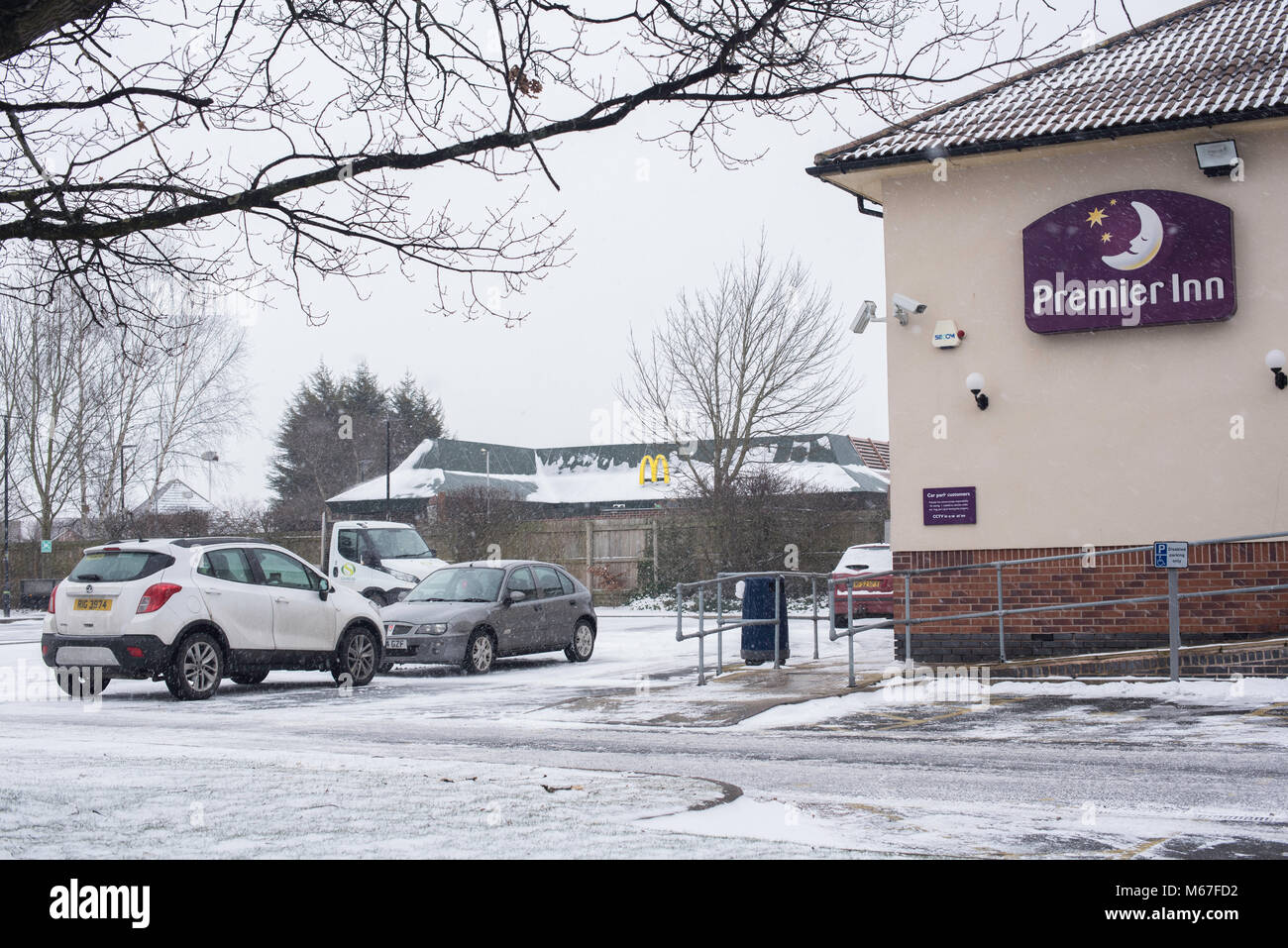 Icy and snow covered pathways outside a premier Inn and a Mcdonalds restaurant as winter continues  into March 2018 Stock Photo