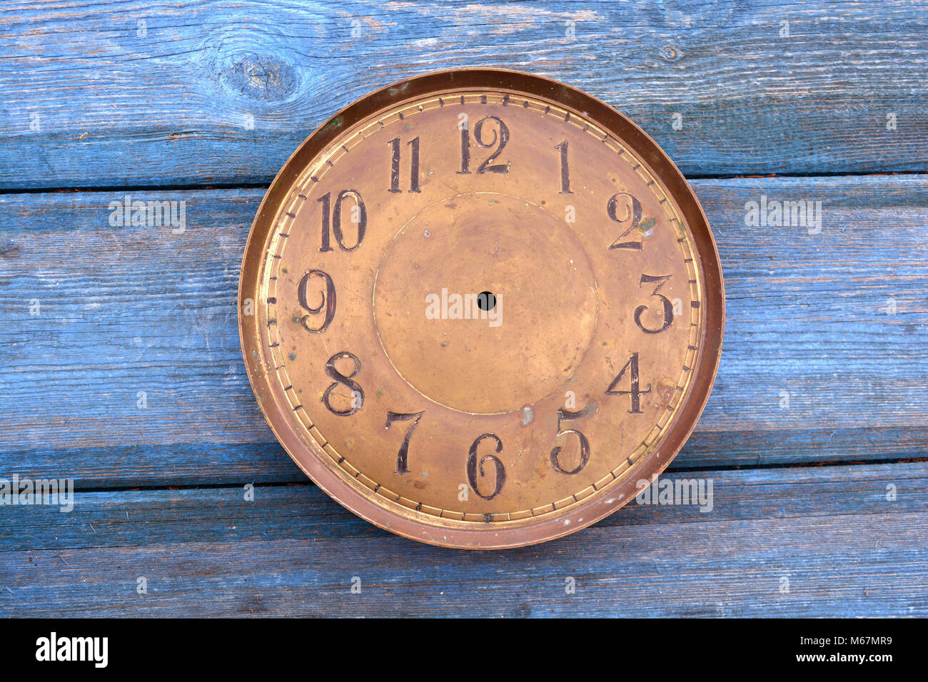 Antique brass clock face dial on old blue wooden background Stock Photo