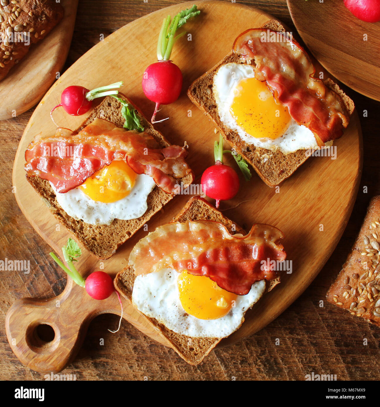 Breakfast , crispy bacon, fried eggs and bread. Sandwiches on cutting board. Rustic table . Top