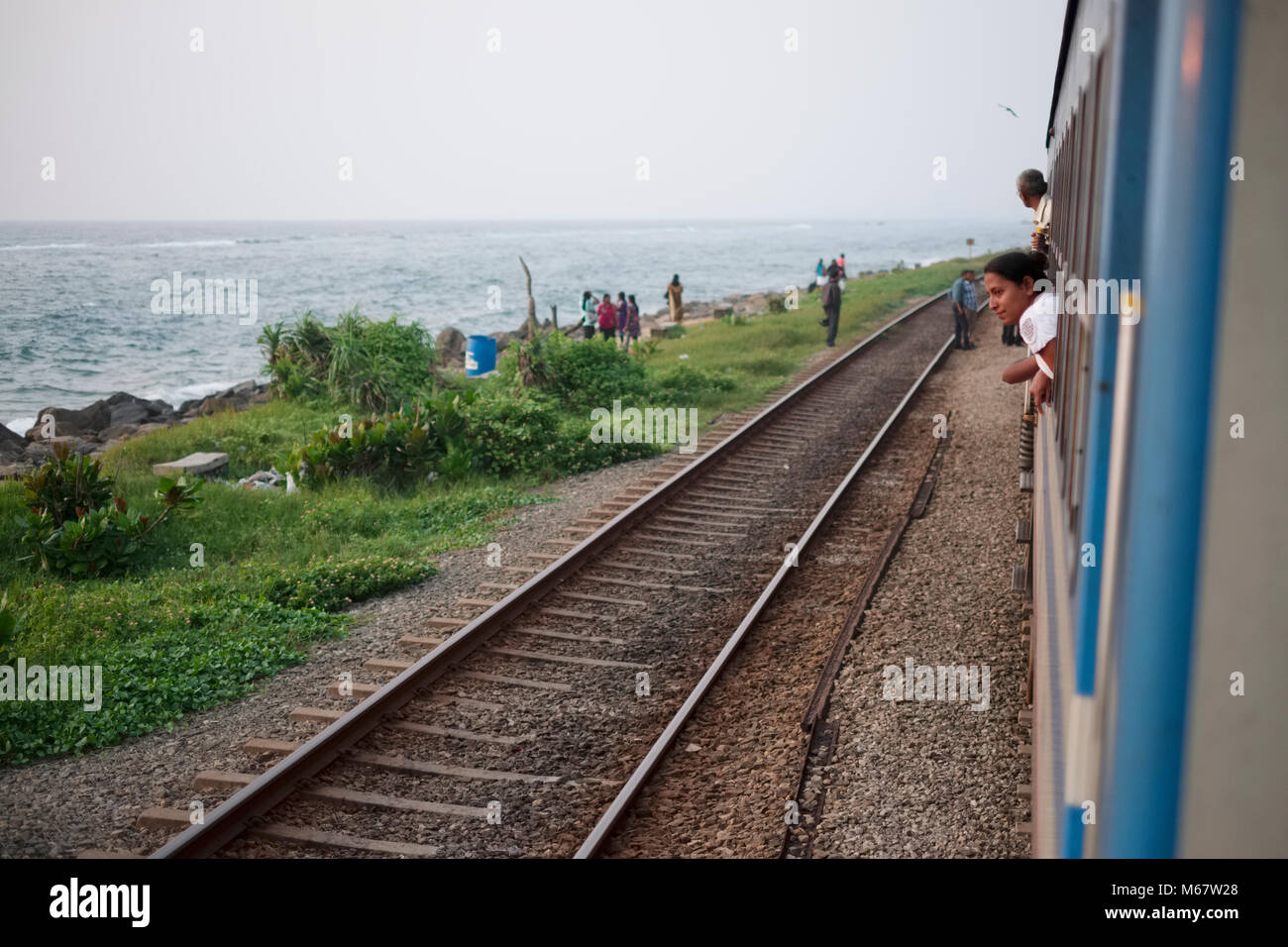 A woman looks out of the train window near Colombo in Sri Lanka Stock Photo