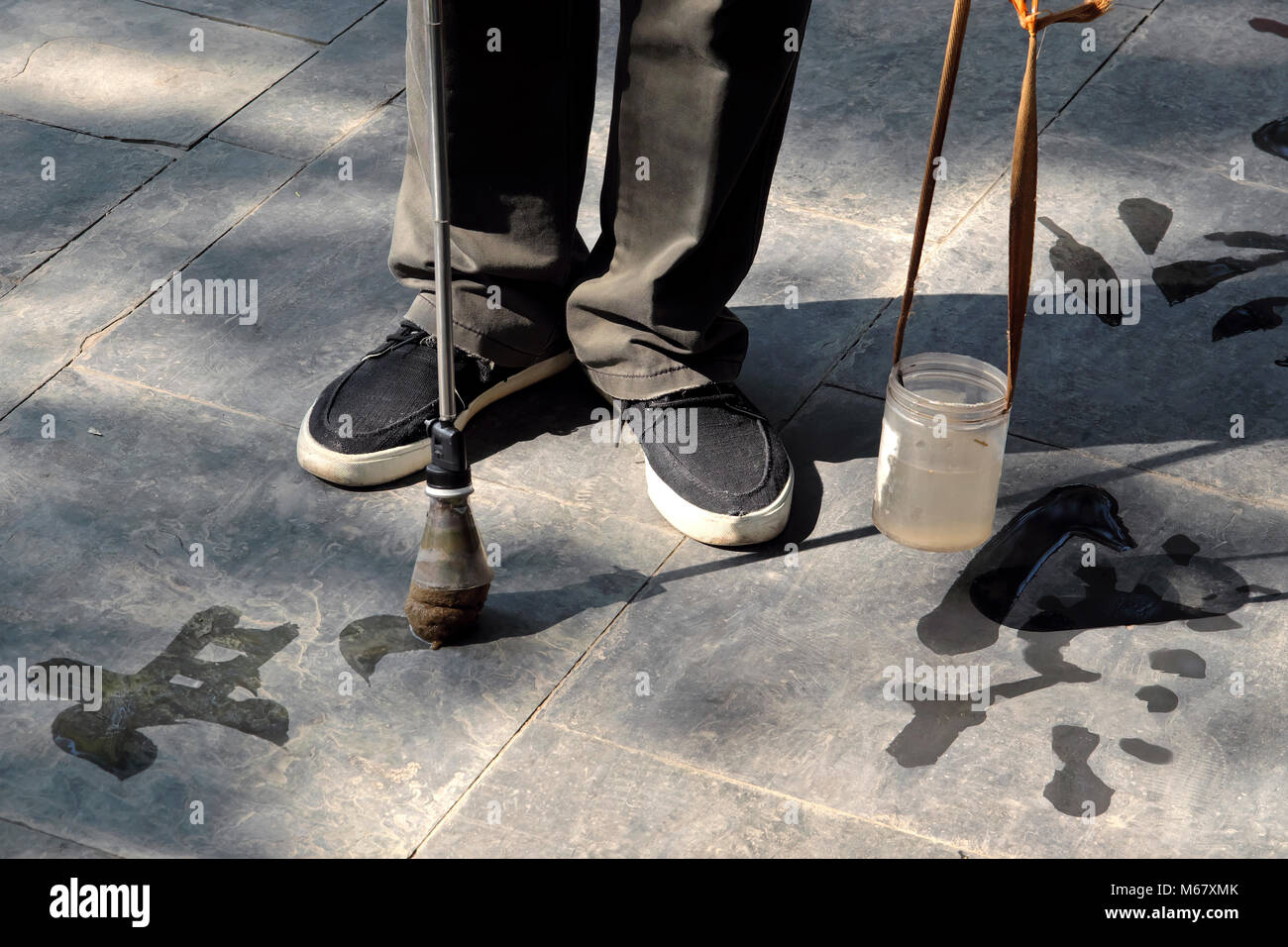 Old man - calligrapher - practicing traditional pavement water calligraphy, The Summer Palace, Beijing, China Stock Photo