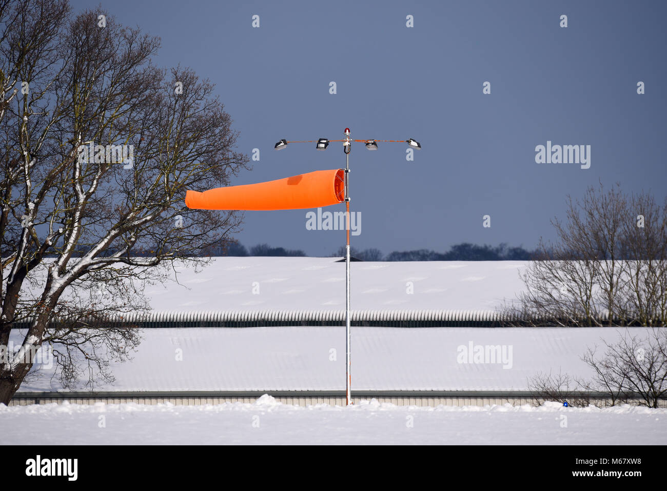 Windsock at snow covered airport. Beast from the east travel disruption at London Southend Airport. Strong wind. Space for copy Stock Photo