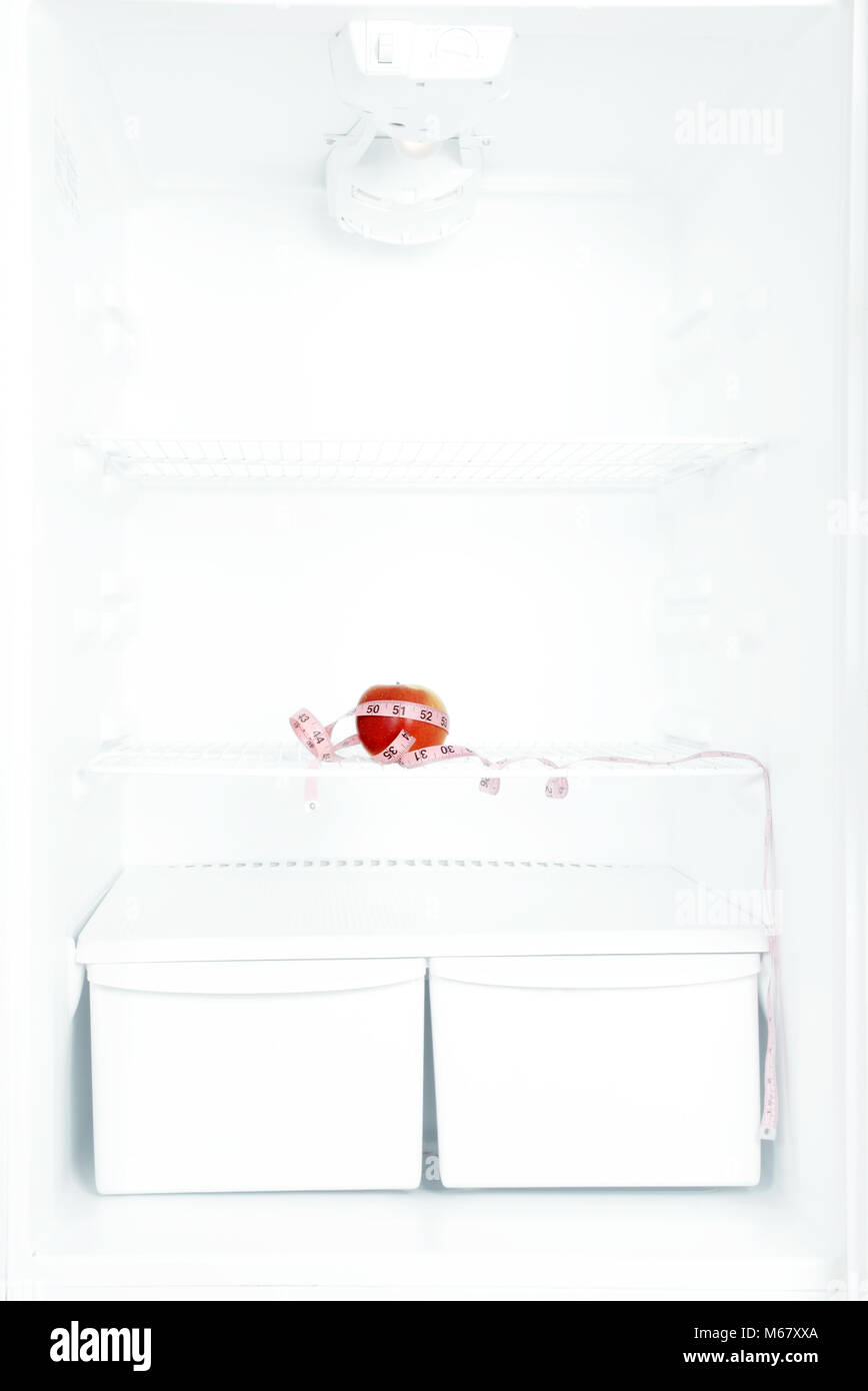 Apple on shelf of open empty refrigerator. Weight loss diet concept