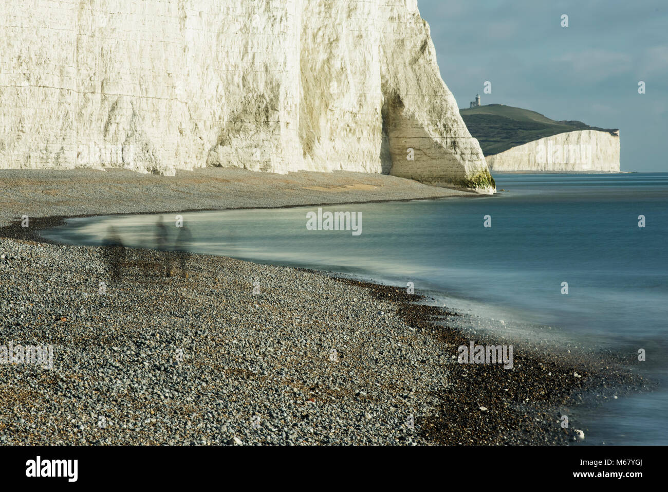 The cliffs of Seven Sisters and ghostly figures with Belle Tout lighthouse in the background, on the Sussex coast on the South Downs Way. Stock Photo