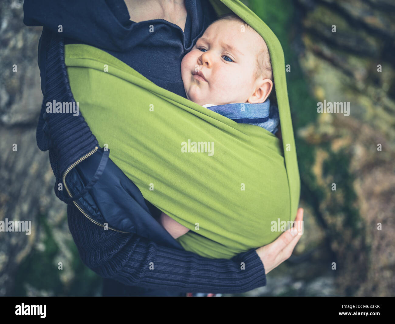 A young mother is standing outside in nature with her baby in a sling Stock  Photo - Alamy