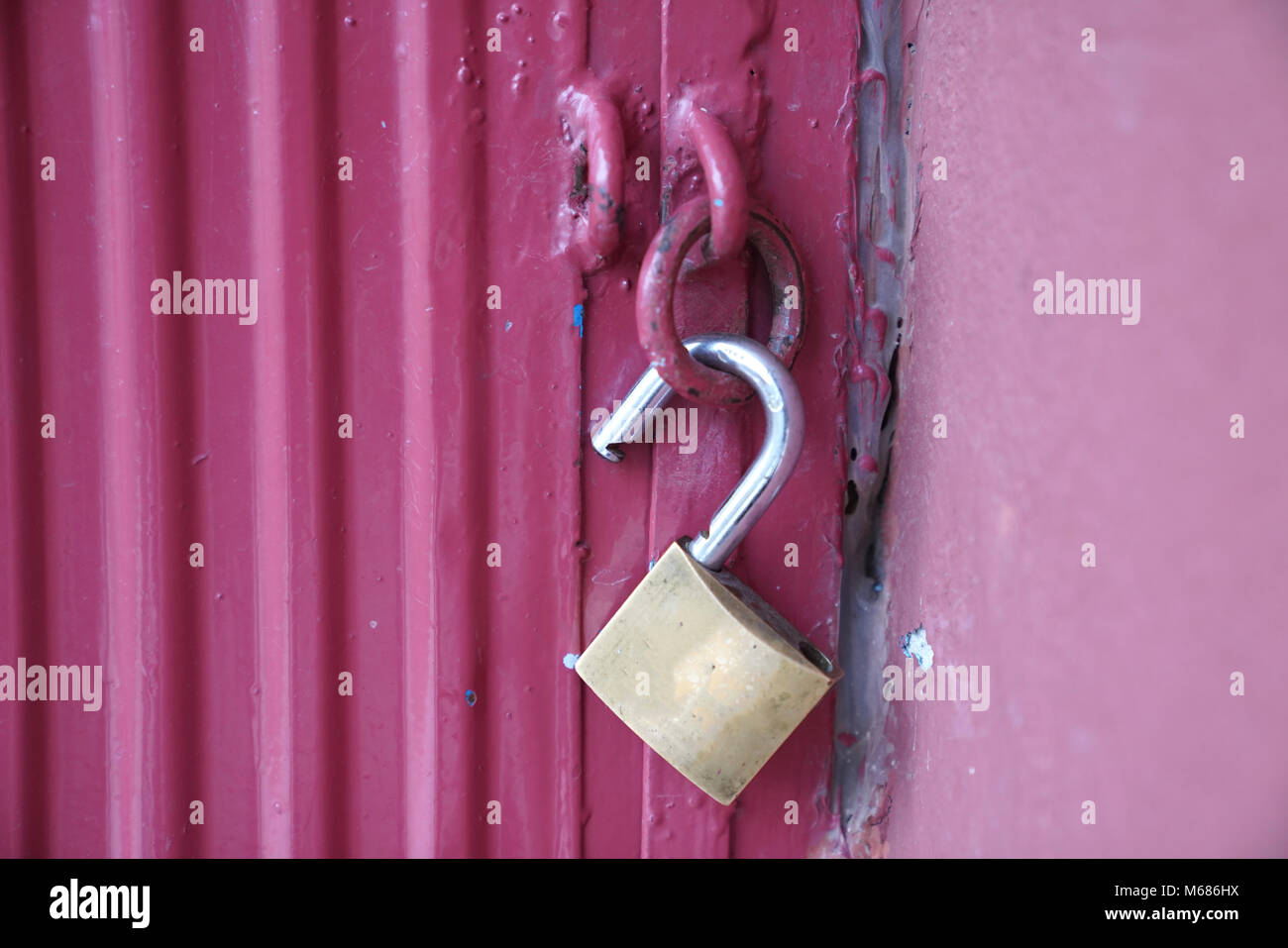 Unlocked brass padlock on a red metal door Stock Photo Alamy