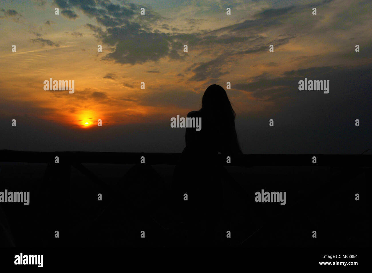 Woman watching sun set Stock Photo - Alamy