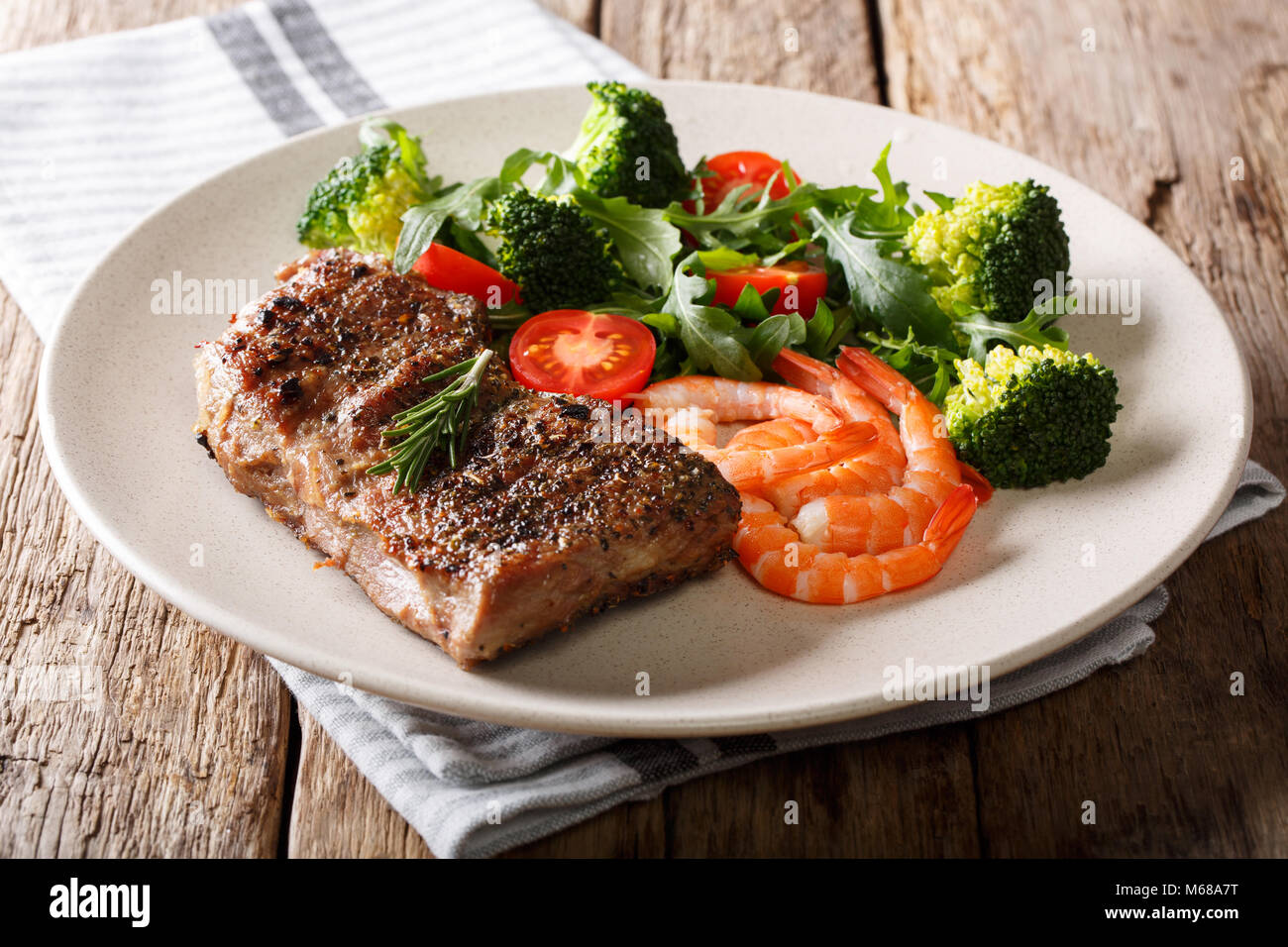 Delicious grilled beef steak with prawns and broccoli, tomatoes, arugula closeup on a plate on a table. Surf and Turf. horizontal Stock Photo