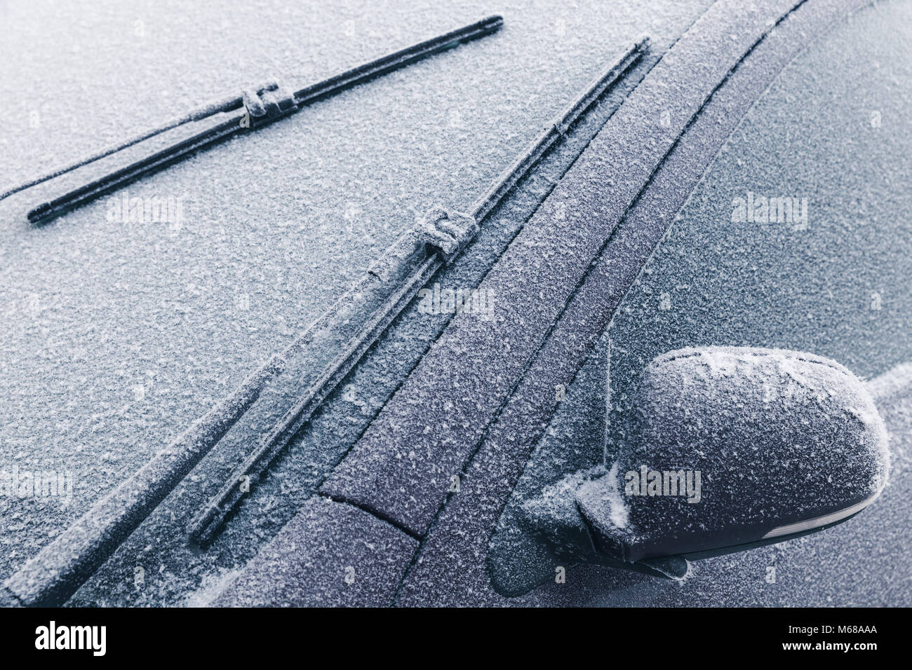 Car wipers on windshield and mirror covered with frost in cold winter