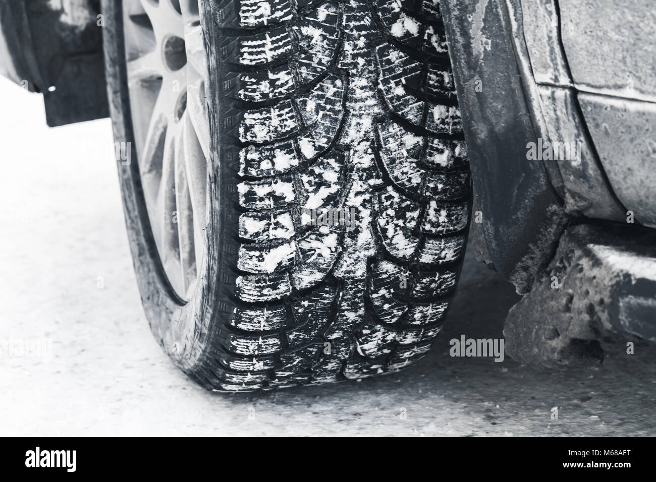 Close-up photo of car wheel on snow tire with metal studs, which improve traction on icy surfaces. Stock Photo