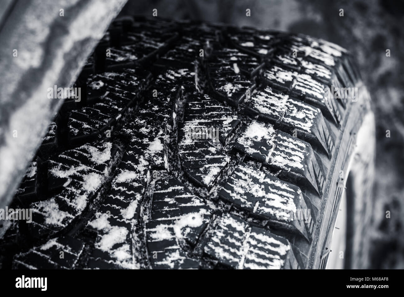 Snow tire with metal studs, which improve traction on icy surfaces, close-up photo of car wheel with selective focus Stock Photo