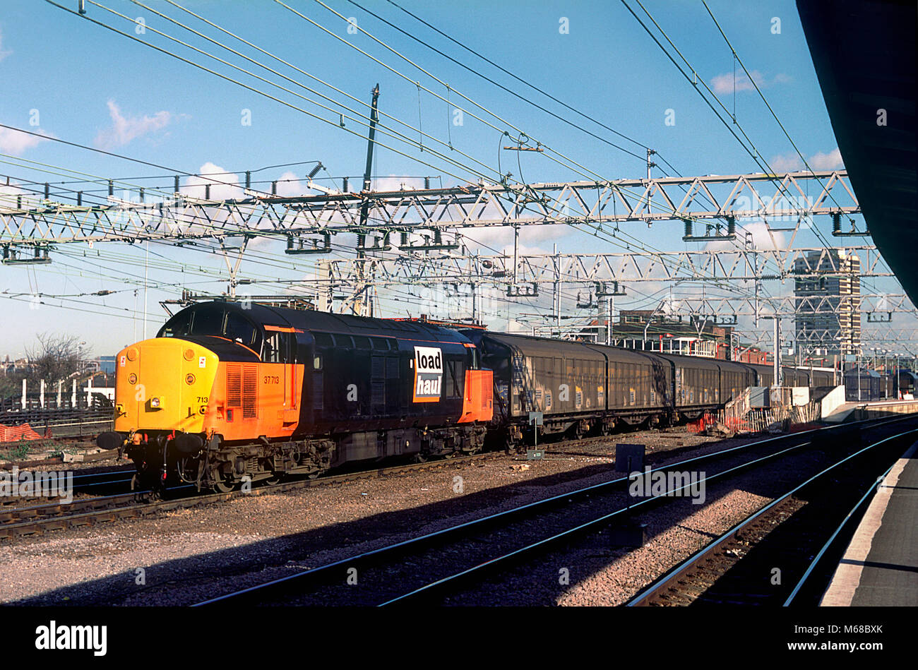 A class 37 diesel locomotive number 37713 in Load Haul livery working a train of Cargo Wagons at Stratford in east London on the 17th February 1995. Stock Photo