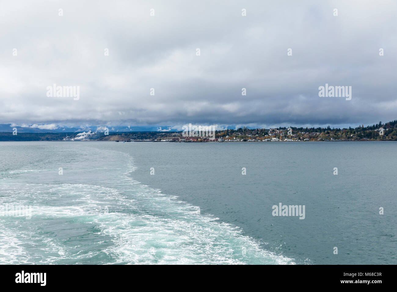Ferry leaving Port Townsend, Washington State with town and paper mill distant Stock Photo