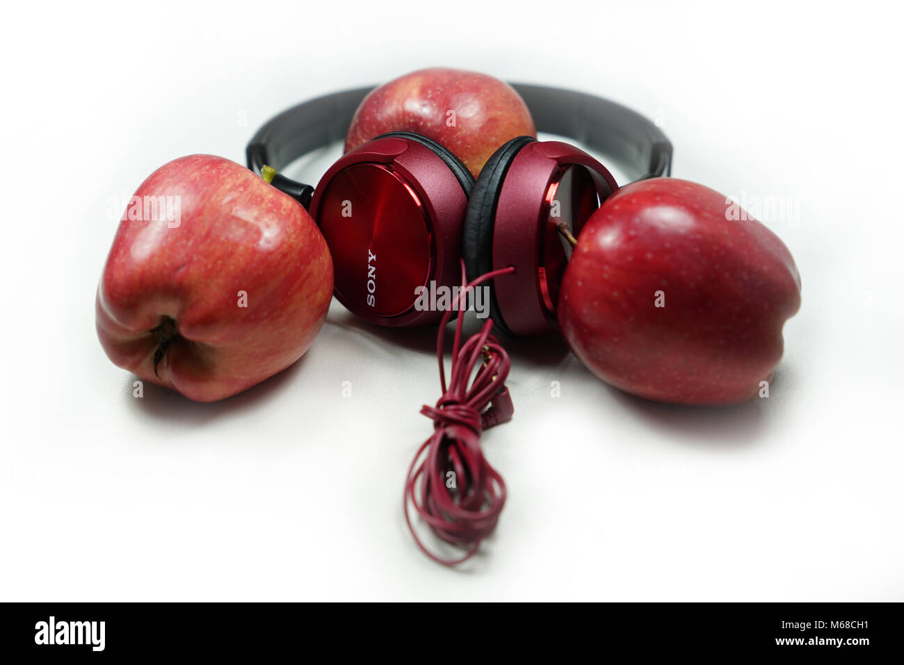 Red apples with red Sony headphones on white-background (Music is food for the soul) Stock Photo