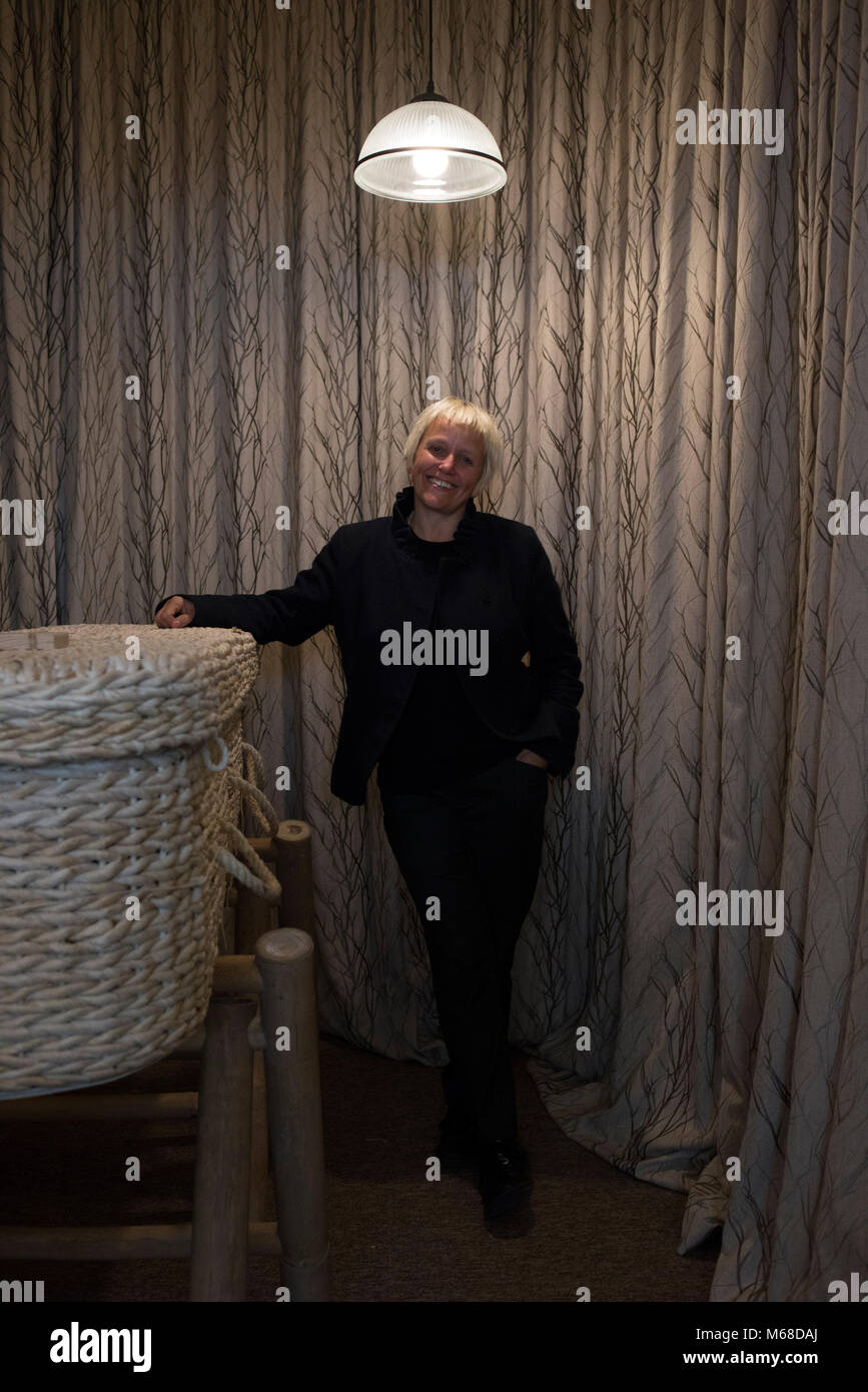 a friendly young funeral director / undertaker stands by a wicker