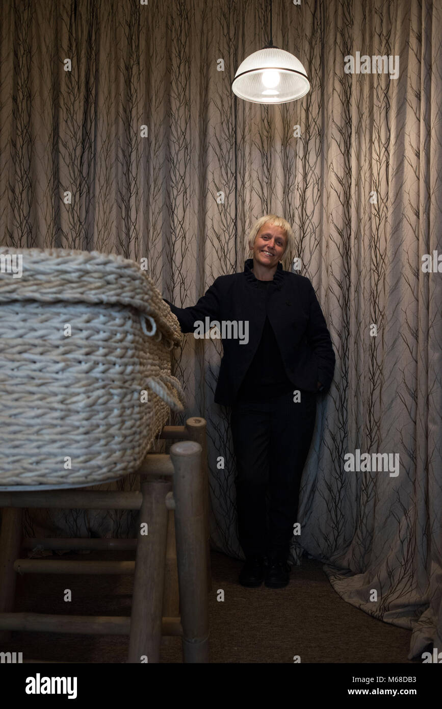 a friendly young funeral director / undertaker stands by a wicker