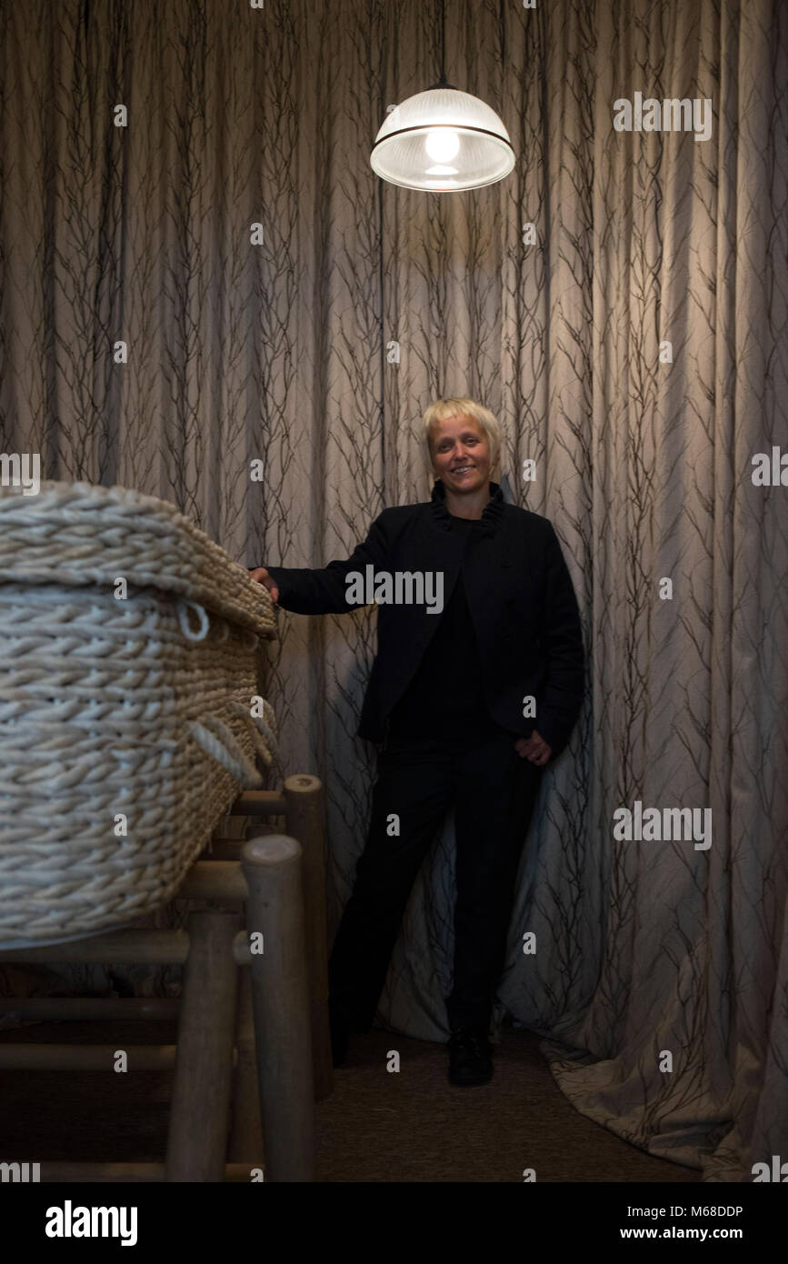 a friendly young funeral director / undertaker stands by a wicker