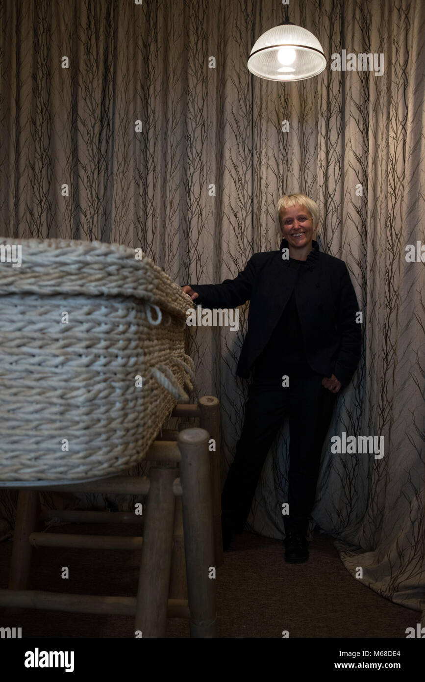 a friendly young funeral director / undertaker stands by a wicker