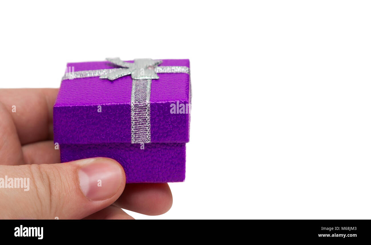 Hand holding small violet color gift with silver ribbon Stock Photo