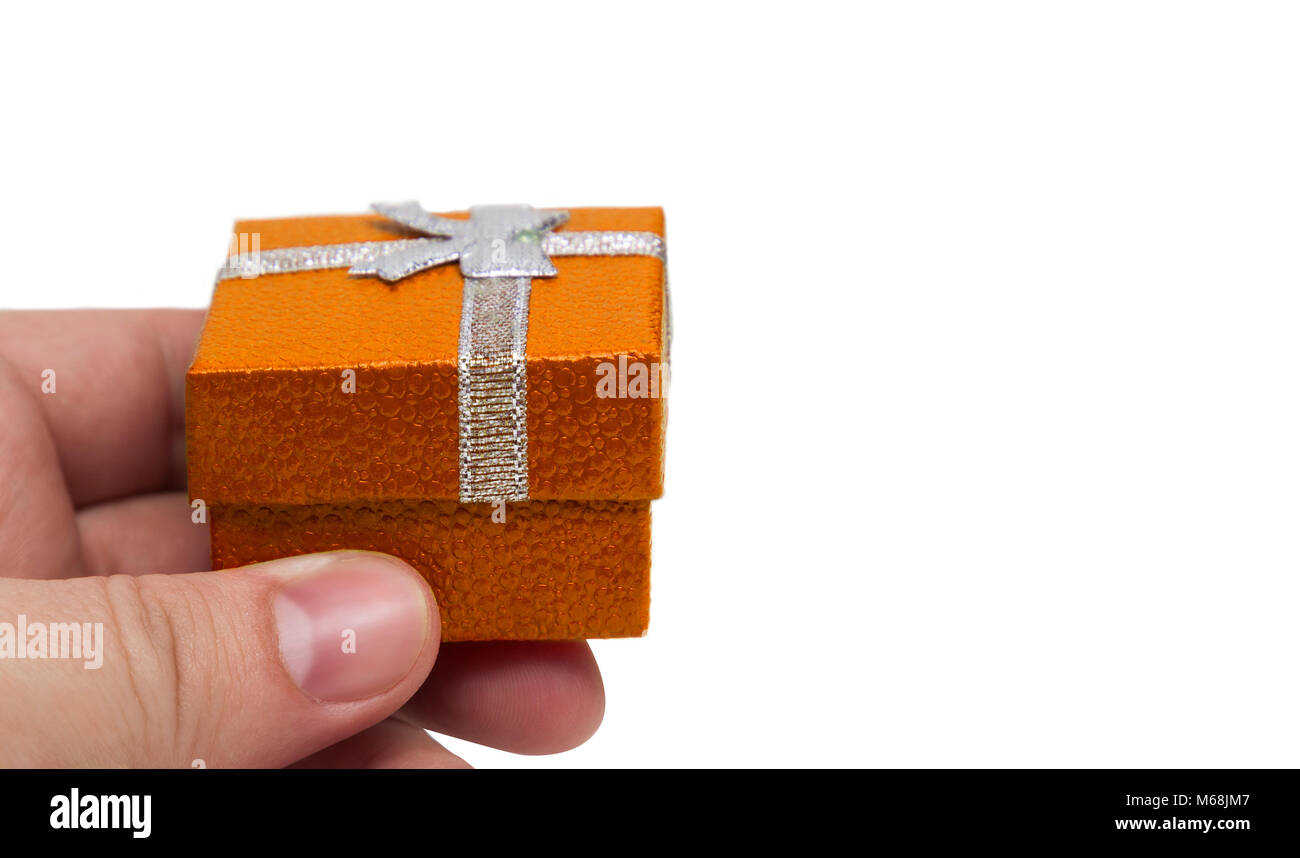 Hand holding small orange color gift with silver ribbon Stock Photo