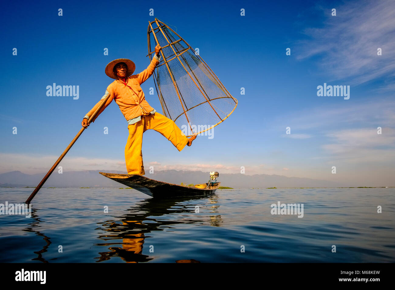A fisherman, standing on his boat, posing, is fishing the traditional way  on Inle Lake Stock Photo - Alamy