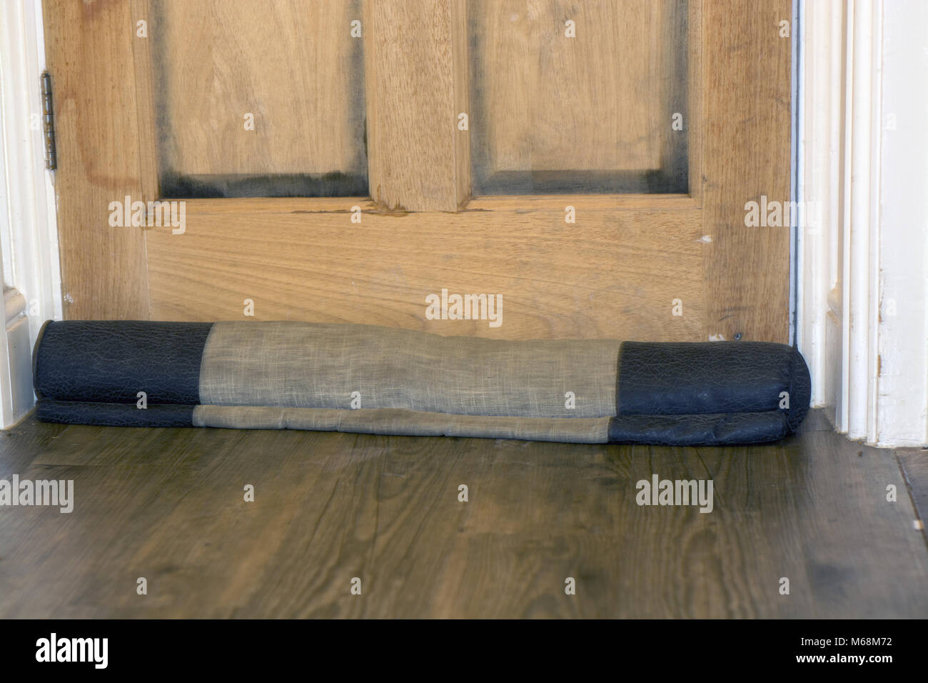 A draft excluder in situ, in front of a door Stock Photo