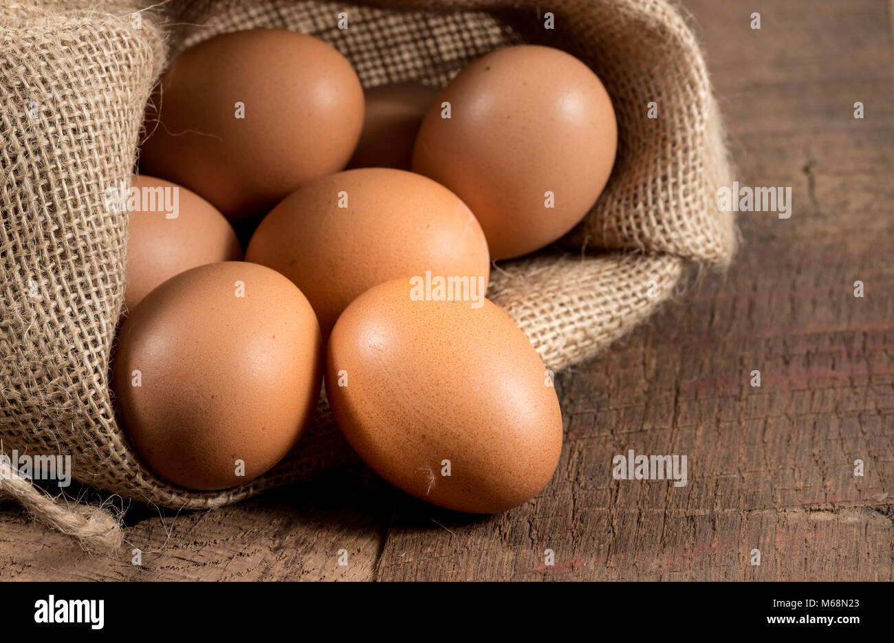 Freshly laid organic eggs in burlap sack on wood Stock Photo