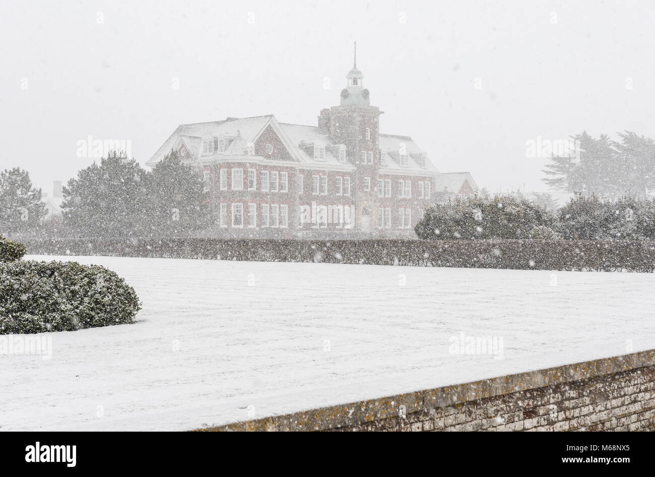 Rustington Convalescent Car Home and surrounding grounds in Winter while snow is falling in Rustington, West Sussex, England, UK. Snow shower. Cold. Stock Photo