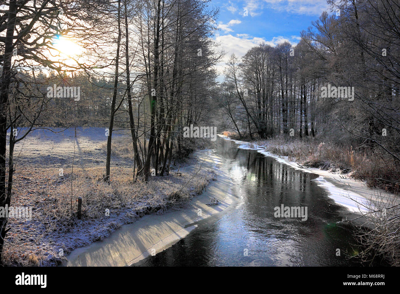 Winter landscape of woods and river covered with ice and snow in