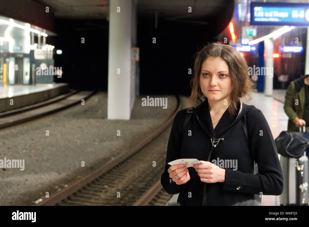 The girl passenger with a ticket in hand waiting for subway train. A woman traveling alone. Stock Photo