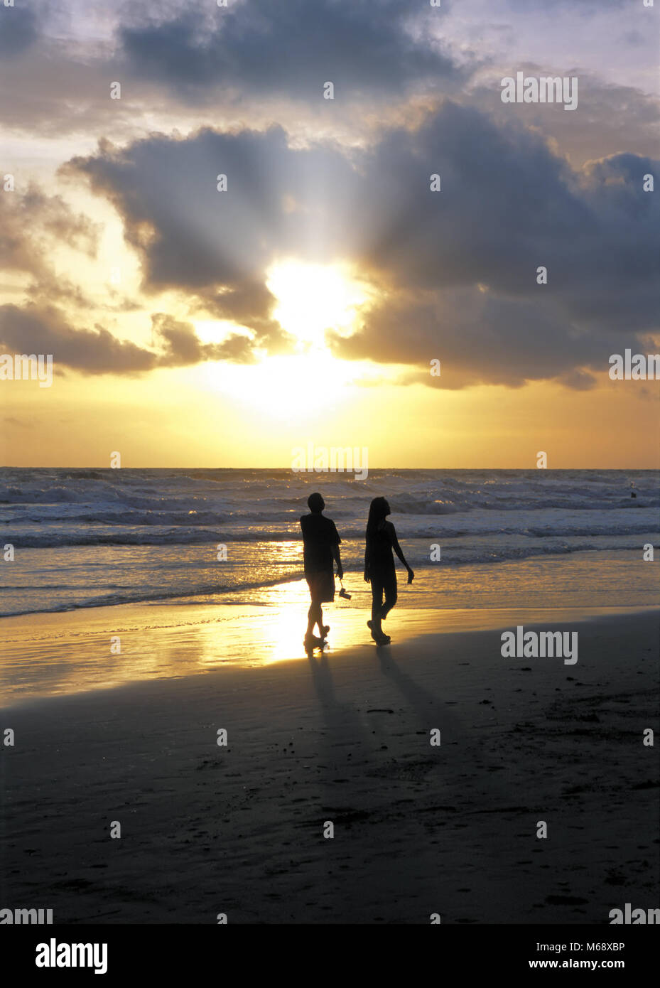 Silhouette of couple walking on the beach against sunset Stock Photo ...