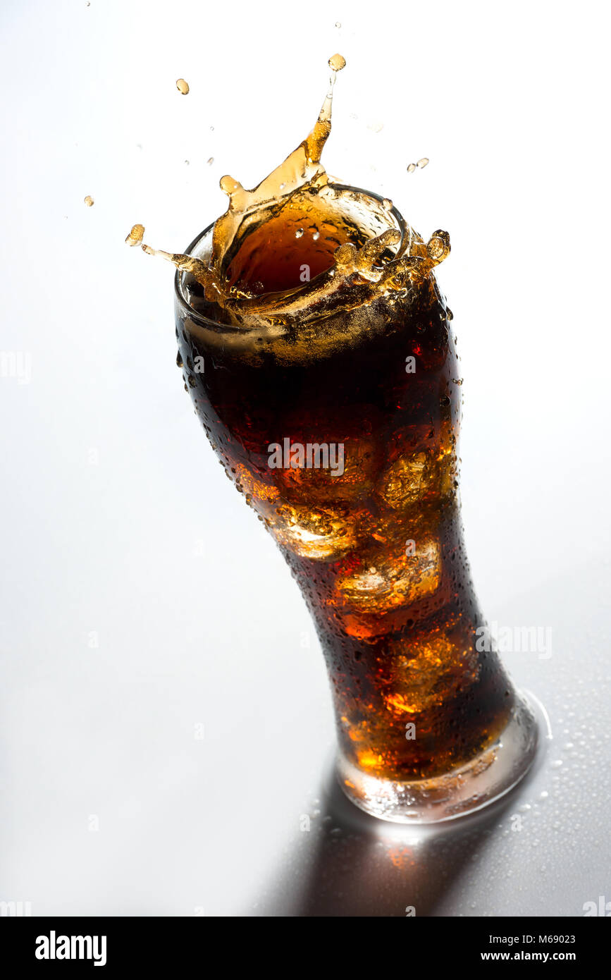 Ice splashing on a glass of a Cola drink against a white background Stock Photo
