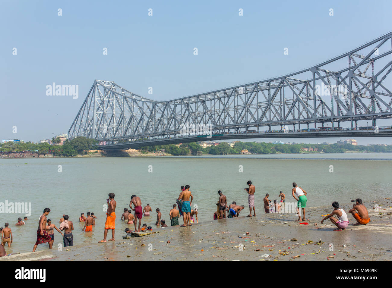 Kolkata, India - April 12, 2017: Unidentified indian people taking bath in Hooghly river with a Howrah bridge on background in Calcutta, West Bengal,  Stock Photo