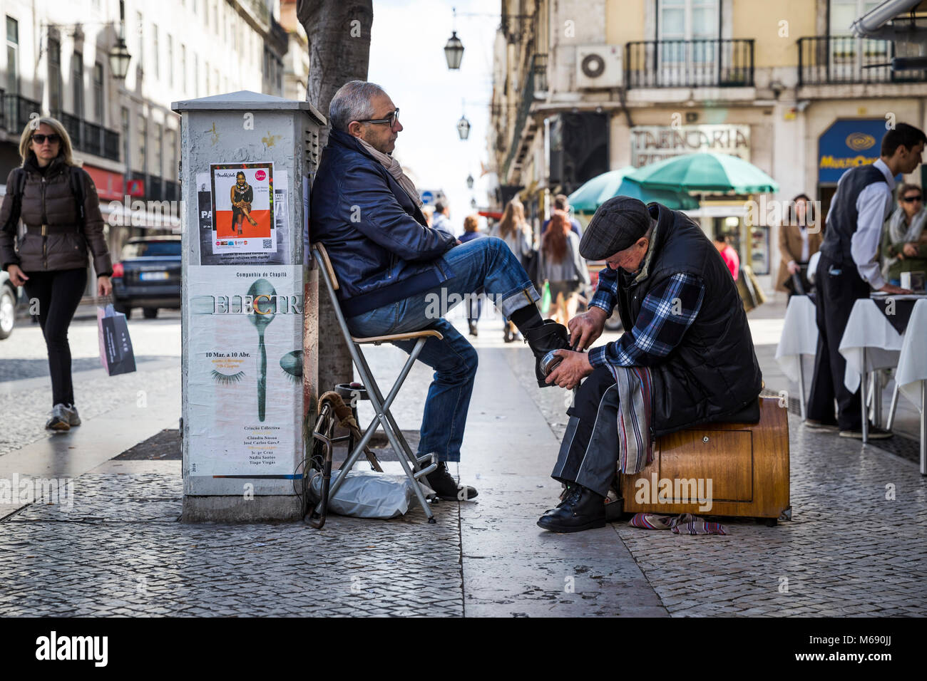 A man has his shoes shined on the street in Lisbon, Portugal. Stock Photo