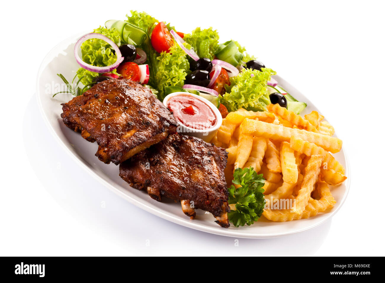 Grilled ribs, French fries and vegetables on white background Stock