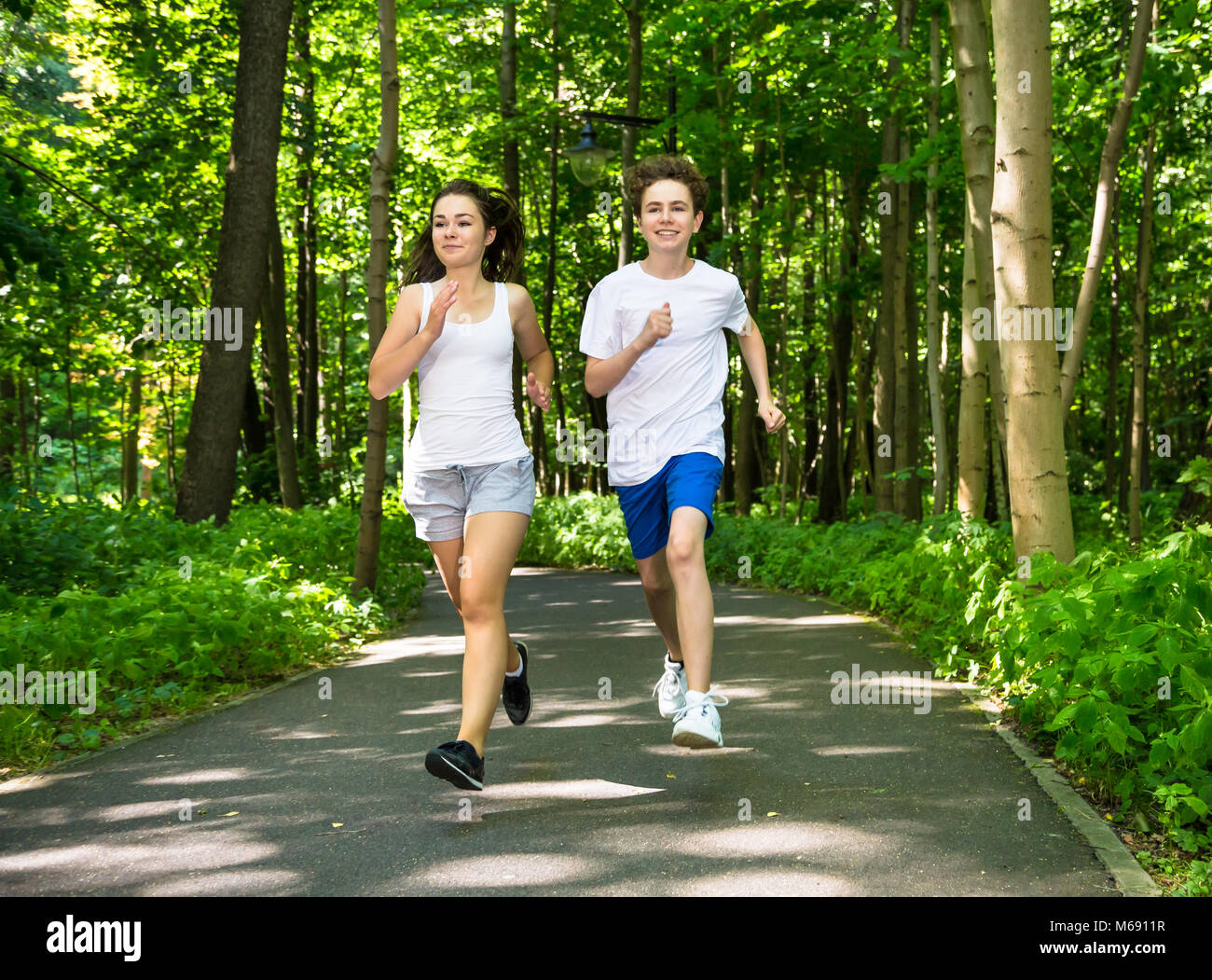 Teenage girl and boy running in park Stock Photo