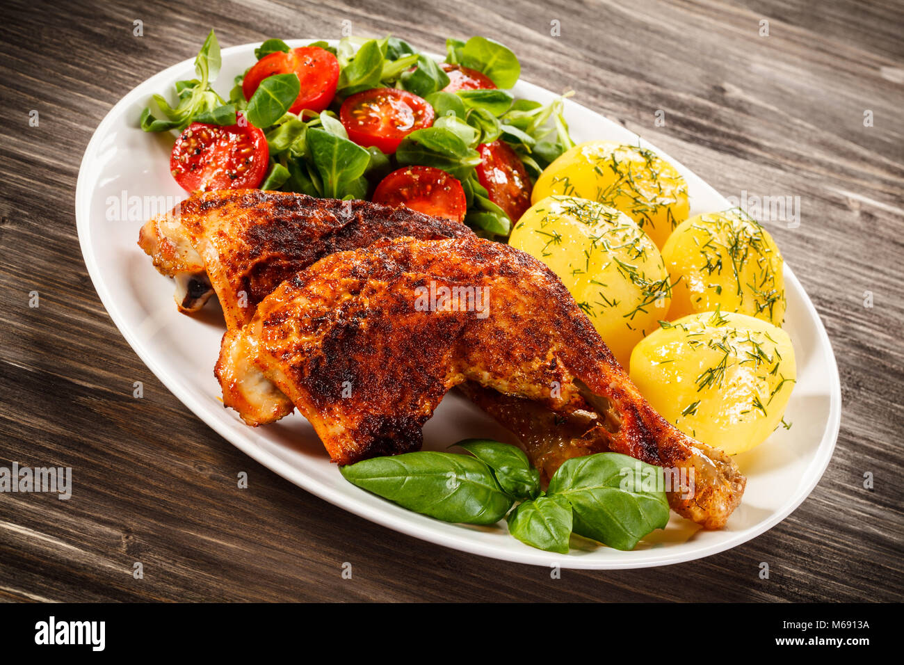 Roast chicken legs with boiled potatoes and vegetable salad Stock Photo