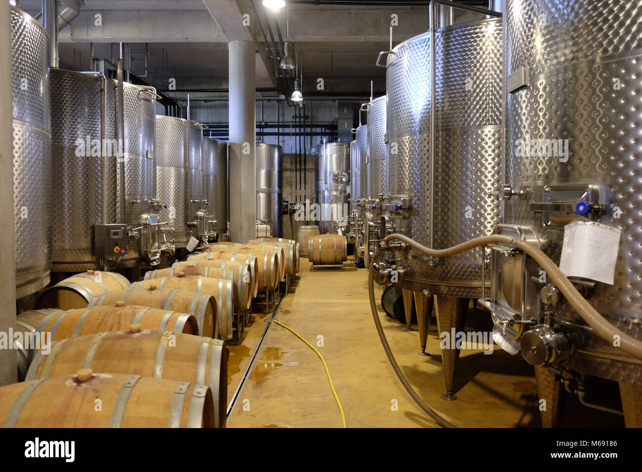 Interior of a modern underground winery with aluminium tanks and wine barrels Stock Photo