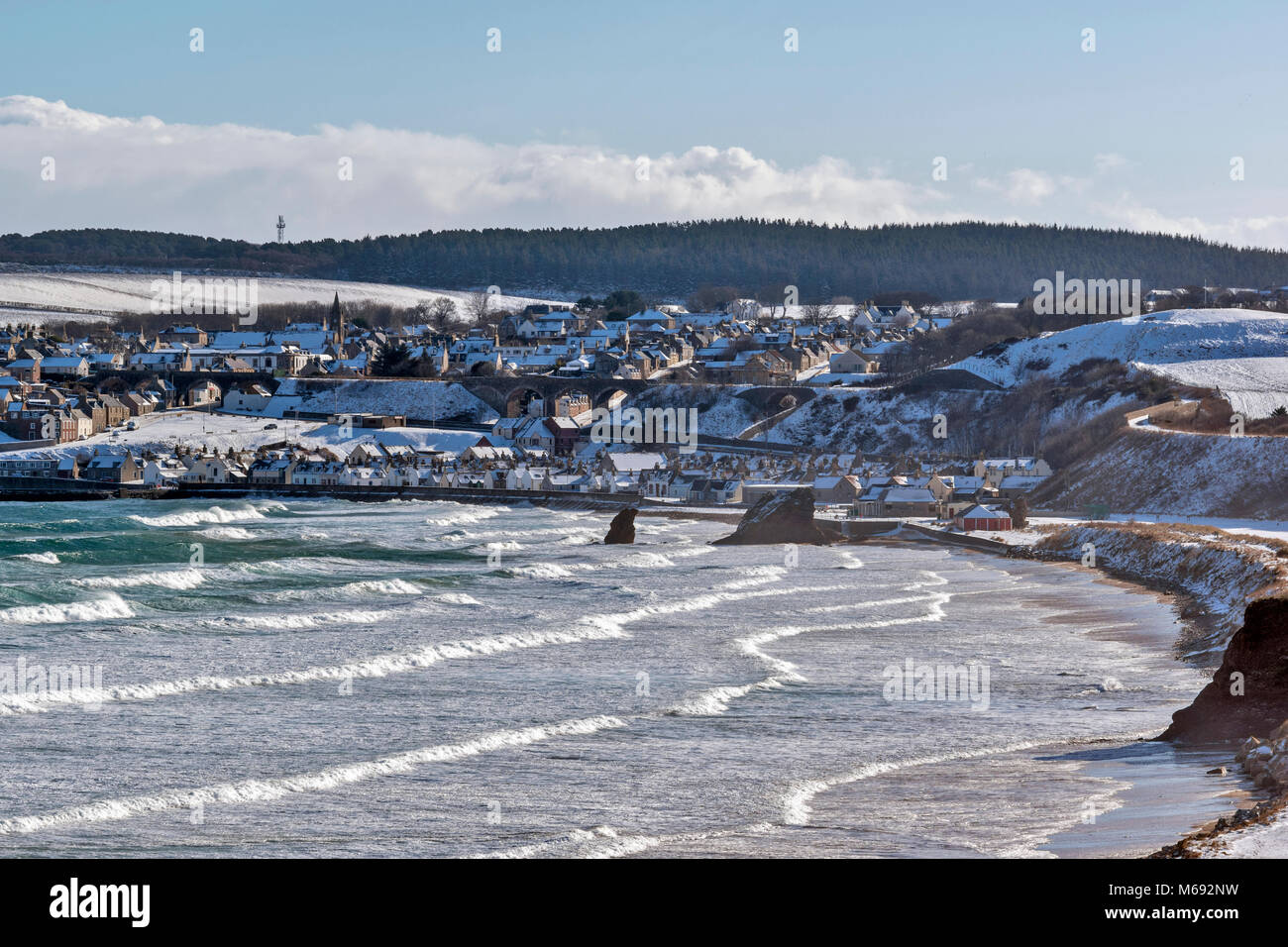 MORAY COAST SCOTLAND CULLEN BAY WITH A STORMY SEA WINTER SNOW ON THE HOUSES IN THE TOWN Stock Photo