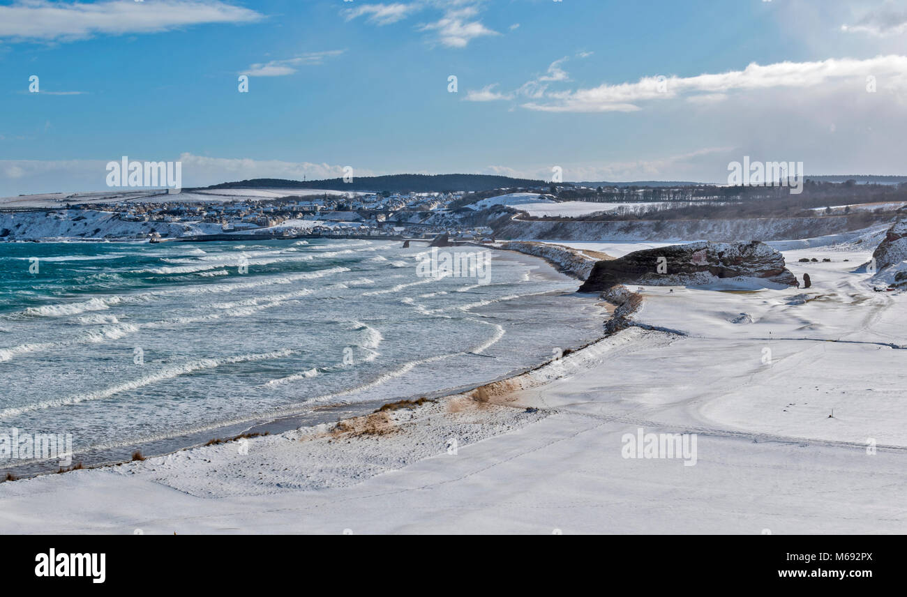 MORAY COAST SCOTLAND CULLEN BAY WITH STORMY SEA AND TOWN COVERED IN WINTER SNOW Stock Photo