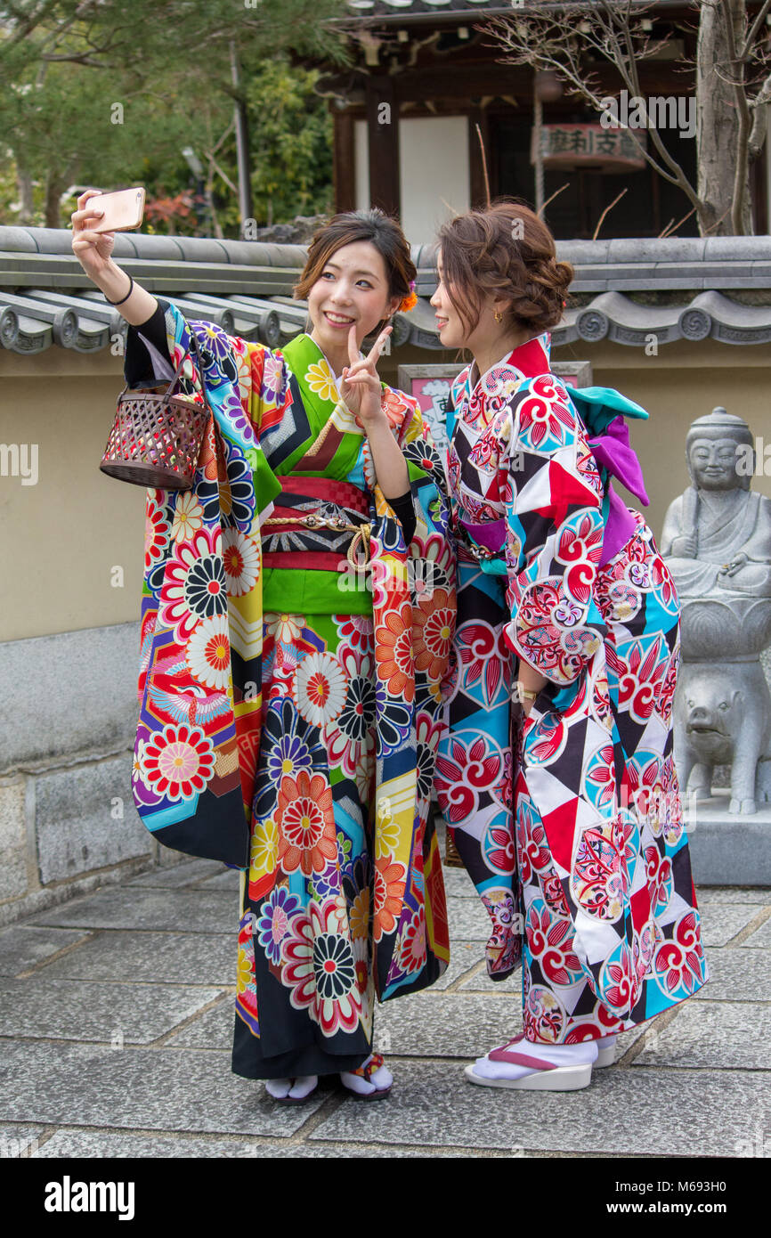 Two girls taking a selfie who have hired traditional Japanese costumes are pictured in the Gion area of Kyoto, Japan near the Kiyomizu-dera Temple. Stock Photo
