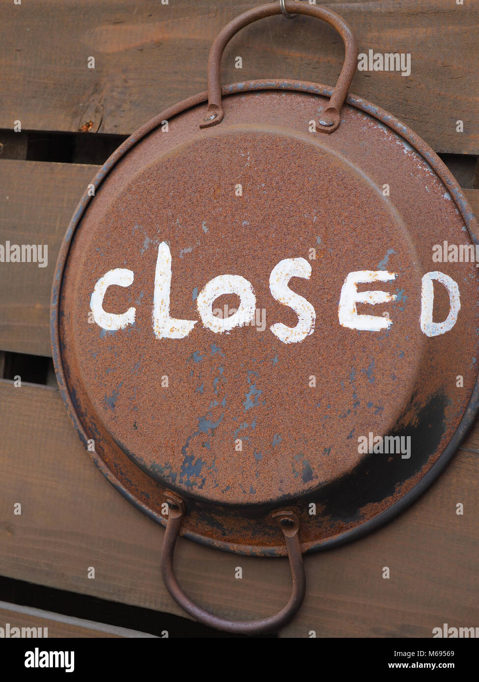 Rustic country handmade Restaurant Closed sign painted on pan. Casually painted on an old frying pan, rough white paint and hung on hook Stock Photo