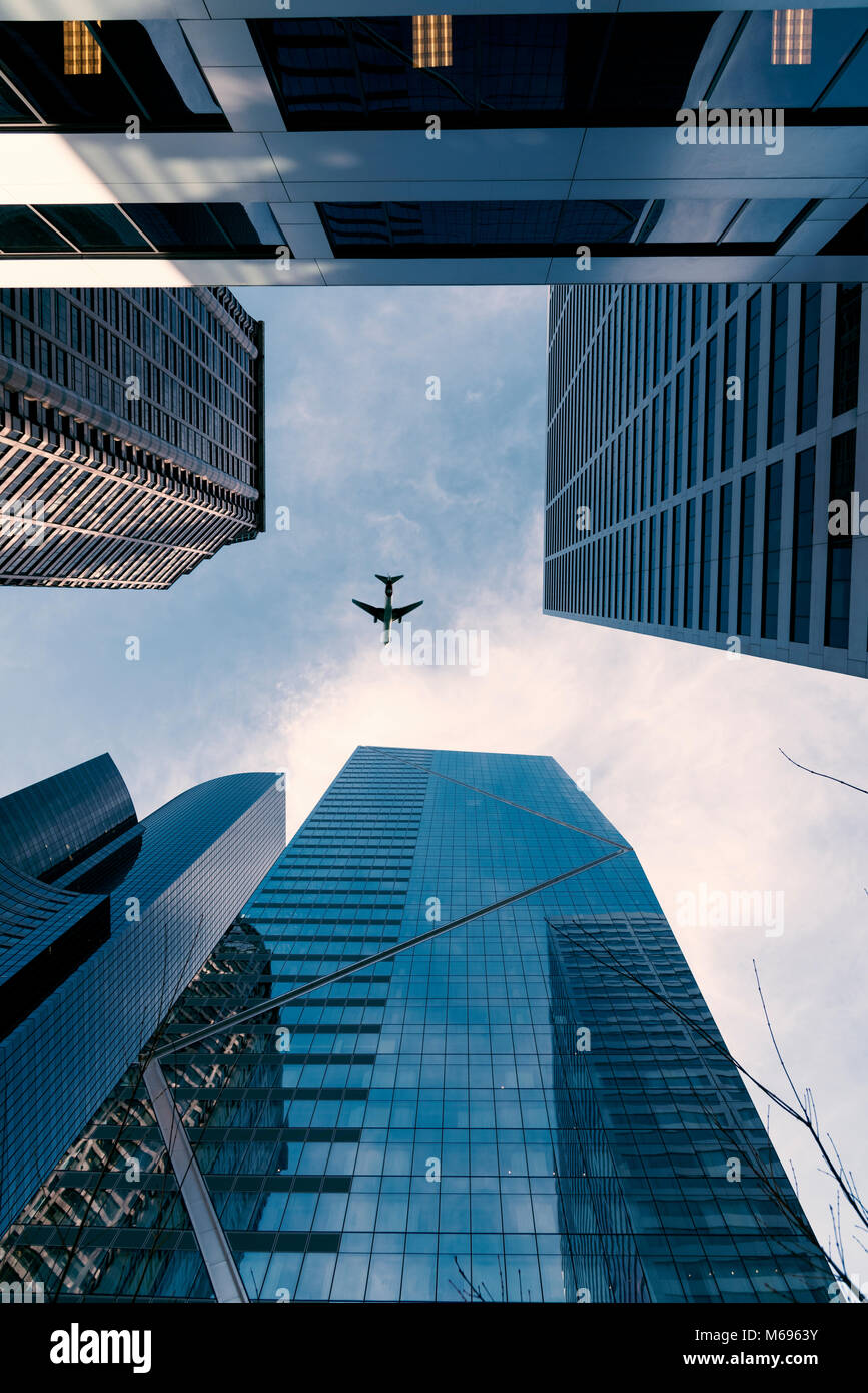 Looking up at the F5 tower and an airplane flying under partly cloudy blue sky vertical portrait. Stock Photo
