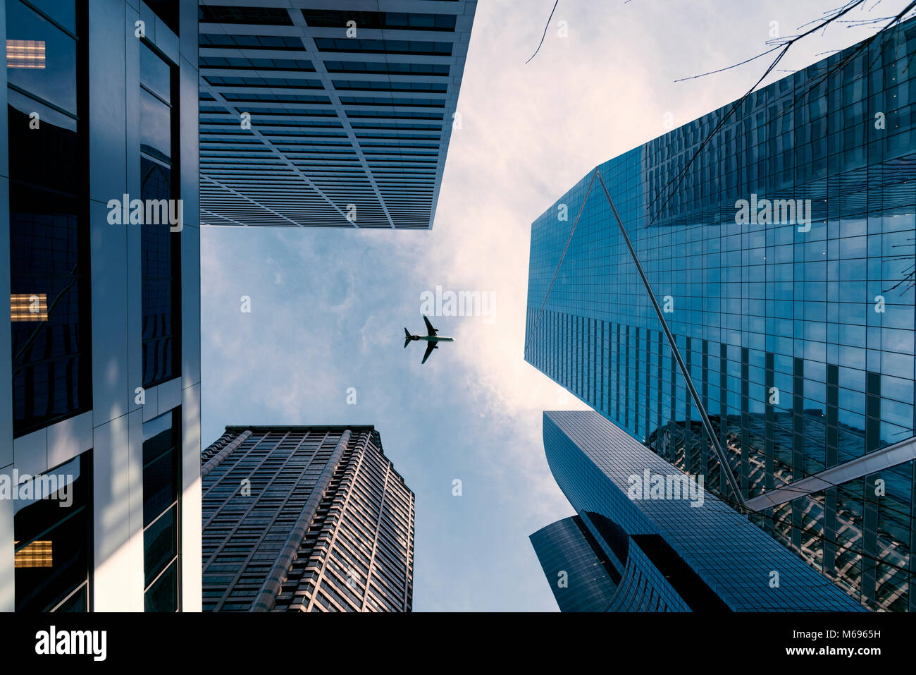 Looking up at the F5 tower and an airplane flying under partly cloudy blue sky horizontal landscape. Stock Photo