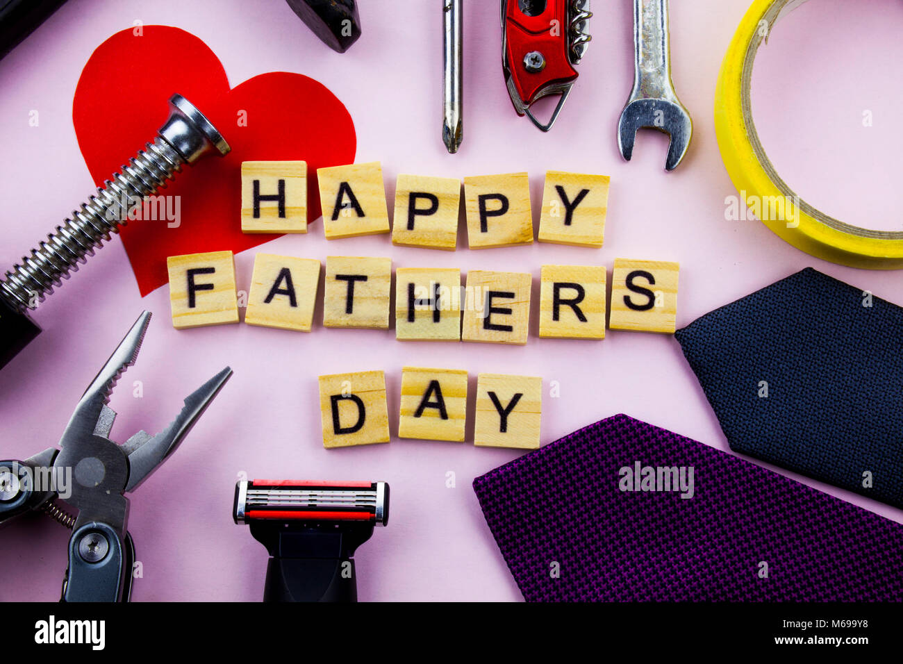 Happy Fathers Day message on a plain pink background with frame of tools and ties. FATHERS DAY. Stock Photo