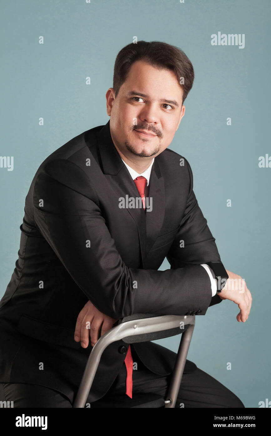 Portrait of acting shoot sitting businessman, little smile on face