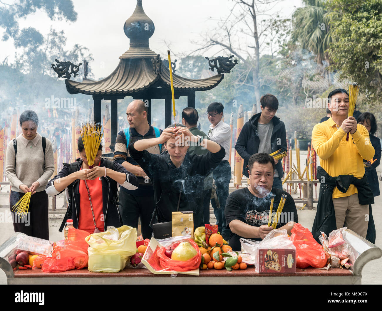 19 February 2018 - Ngong Ping, Lantau Island, Hong Kong. Asian people praying at Po Lin monastery with burning joss incense sticks. Stock Photo