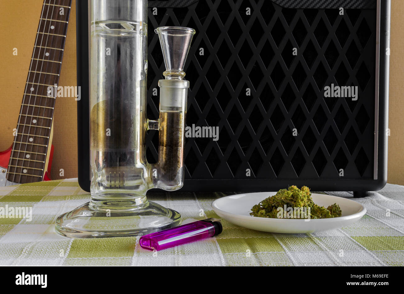 A transparent crystal bong weed, a plate full of marihuana and a purple