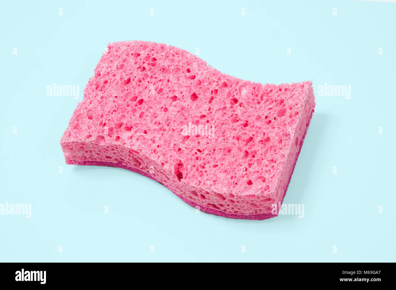 Pink sponge for dishes on faded pastel background. Cleaning tool